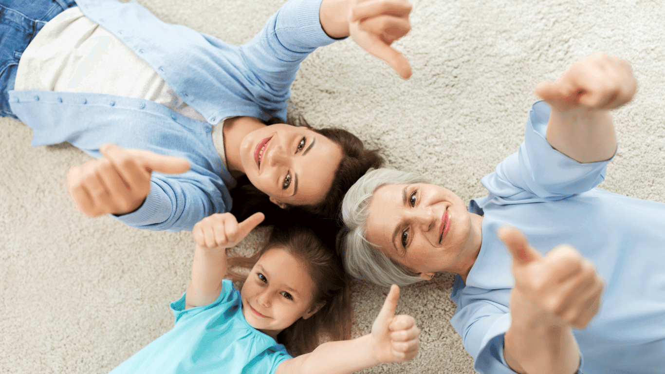 Family of 3 laying on freshly cleaned carpet giving thumbs up representing quality carpet cleaning results and customer satisfaction