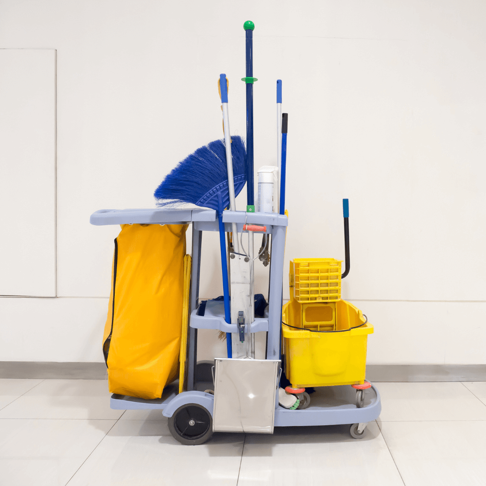 Janitorial cleaning cart with yellow mop bucket, brooms, and supplies in a clean hallway representing professional janitorial services